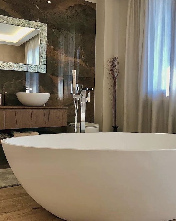 Bagno con vasca freestanding bianca e doppio lavabo su piano in legno